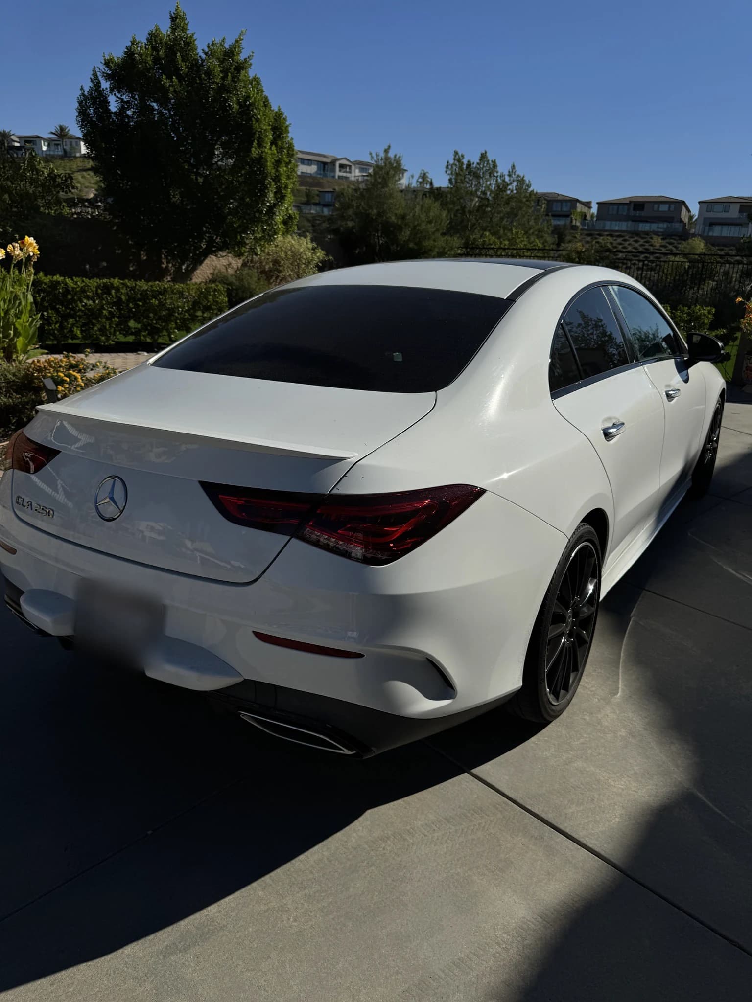 CarPluggLA's white Mercedes-Benz CLA 250, rear three-quarter view on a sunlit driveway